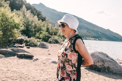 Senior woman wearing sunglasses standing on land against mountains