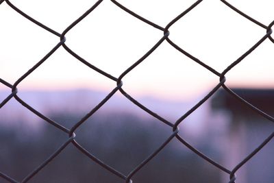 Full frame shot of chainlink fence against sky during sunset