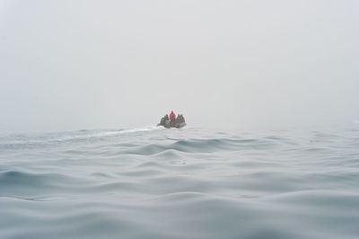 People in jet boat at sea against sky