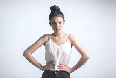 Portrait of young woman standing against white background