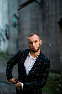 Portrait of young man standing against built structure