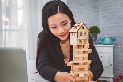 Businesswoman with model home on block removal game at desk