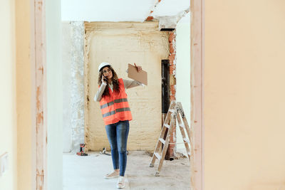 Architect woman in construction site talking on mobile phone and blueprints.home renovation