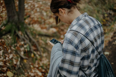 Midsection of woman using mobile phone in forest