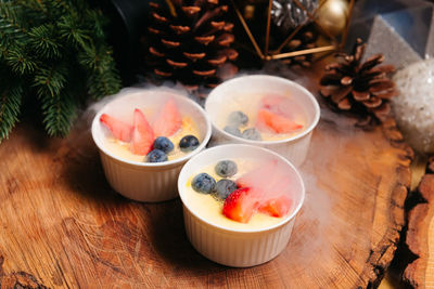 Crema catalana with wild berries in the nitrogen clouds three small servings on a wooden background