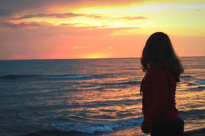 Woman standing on beach during sunset