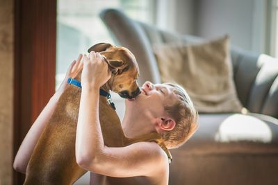 Happy boy playing with dog at home