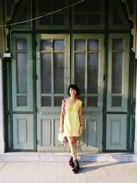 Portrait of smiling young woman standing against door