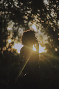 Silhouette woman holding sparkler at sunset