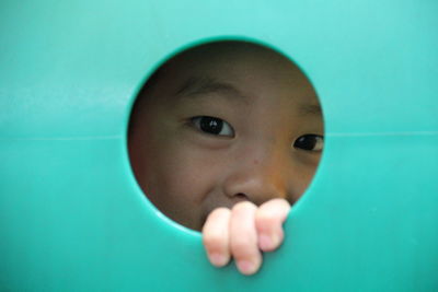 Close-up of cute girl peeking through hole