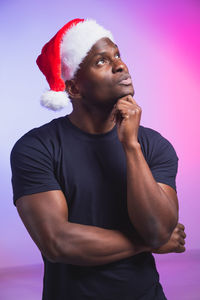 Young man looking away while standing against gray background