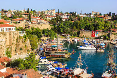 Sailboats moored at harbor by town against sky