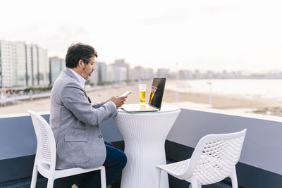 Midsection of man using mobile phone while sitting on table