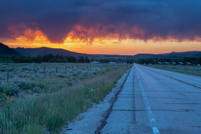 Road by landscape against sky during sunset