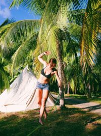 Full length of woman wearing bikini top and hot pants standing on field