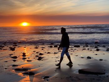 Full length of man standing on beach during sunset