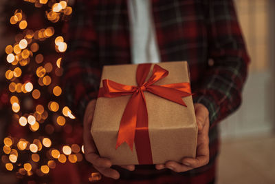 Midsection of man holding christmas present at home