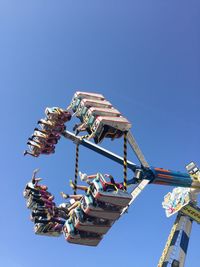 Low angle view of chain swing ride against clear blue sky