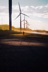 Windmills on field against sky during sunset