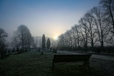 Empty benches in park during winter against sky