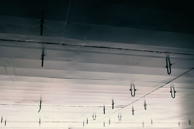 Low angle view of birds on cable against sky