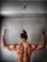 Rear view of shirtless man with arms raised