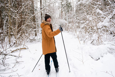 Full length of young man skiing on snow covered field