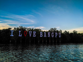 Text on swimming pool by lake against sky