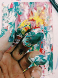 Close-up of hand with messy paints on fingers