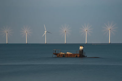 Wind turbines on sea shore against sky