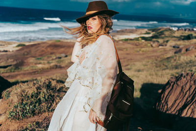 Portrait of woman wearing white dress while standing at beach