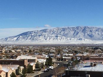 Town on snow covered mountain against cloudy sky