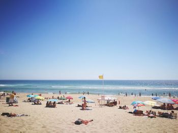 People at beach against clear sky