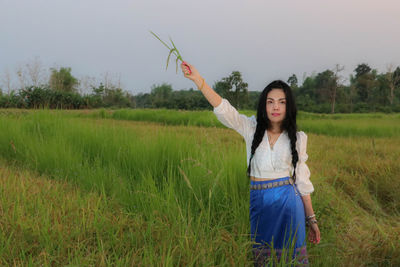 Portrait of young woman standing on field