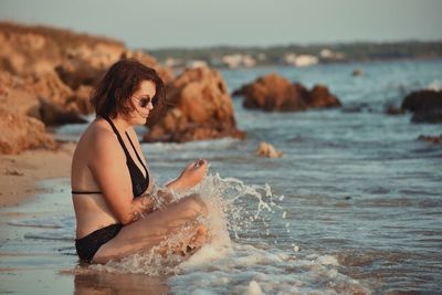 Young woman on shore at beach against sky