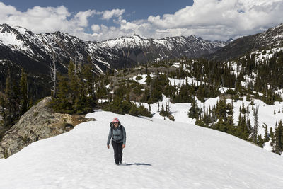 Female hiker walking in snowy mountains on sunny spring day