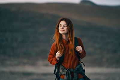 Portrait of beautiful young woman standing against sea