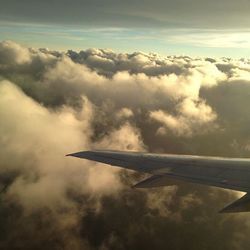 Cropped image of airplane flying over clouds