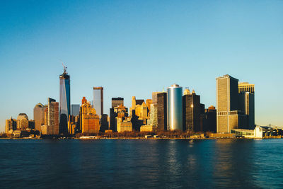 Sea by modern buildings against clear sky