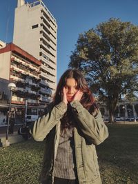 Portrait of young woman standing against building