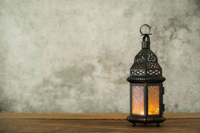 Close-up of lantern on table against wall