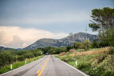 Road by mountains against sky