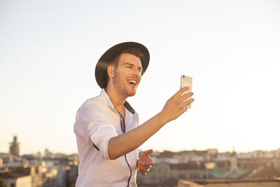 Handsome young singer performing for his fans on social media from the roof of his house during quarantine