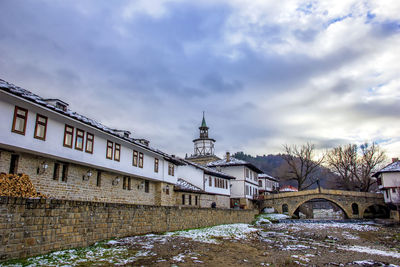 Bridge by buildings against sky during winter