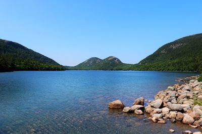 Scenic view of lake and mountains against clear blue sky