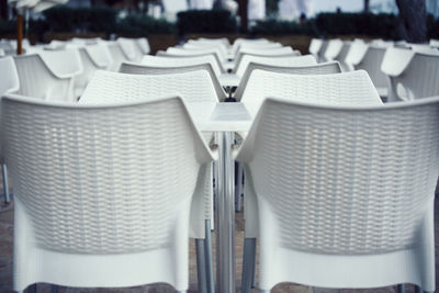 Close-up of empty white chairs at outdoor cafe