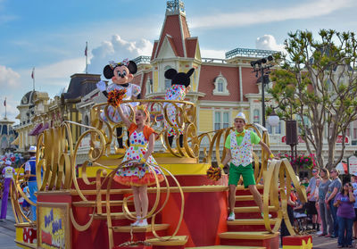 People at amusement park ride against sky