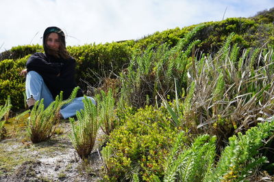 Portrait of young woman sitting amidst plants