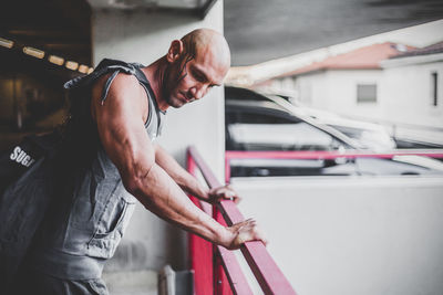 Side view of muscular man leaning on railing