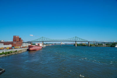 Suspension bridge over river against blue sky